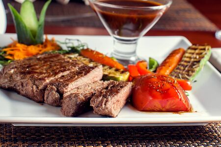 Beef steak with grilled vegetables served on white plateの写真素材