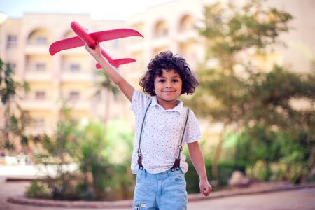 Young happy boy playing with red airplane outdoor. Children and entertainment conceptの写真素材
