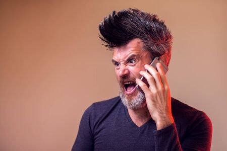 Angry man with beard and iroquis screaming on the phone. People, emotions conceptの写真素材