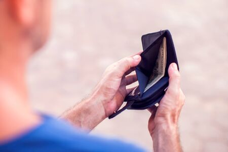 Man holds an empty wallet in hands outdoor. Finance problem concept