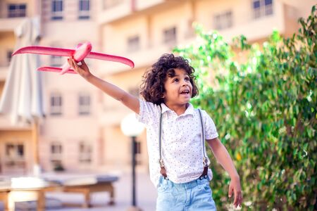 Young happy boy playing with red airplane outdoor. Children and entertainment conceptの写真素材