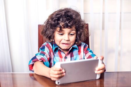 Little boy looking at touch pad at home. Children and technology conceptの写真素材