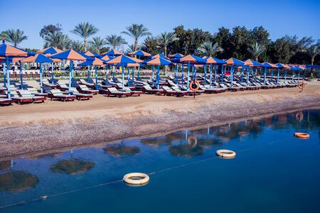 Beach with chaise lounges standing in line on beige sand. Vacation and travel conceptの写真素材