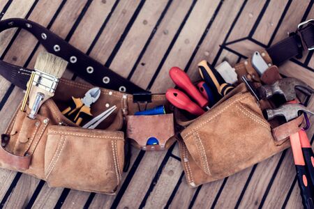 Leather tool belt with construction tooling on wooden board. Maintenance concept.の写真素材