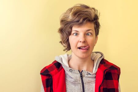 Young woman with short hair making a funny face over yellow background.の写真素材