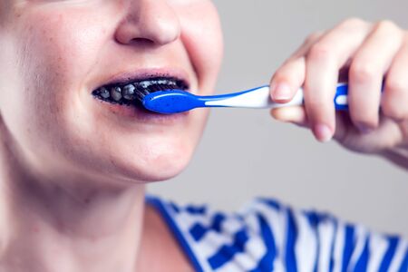Woman cleans her teeth with charcoal toothpaste. People and healthcare concept.の写真素材