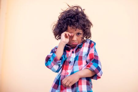 Sad kid with curly hair cry over isolated backgroundの写真素材
