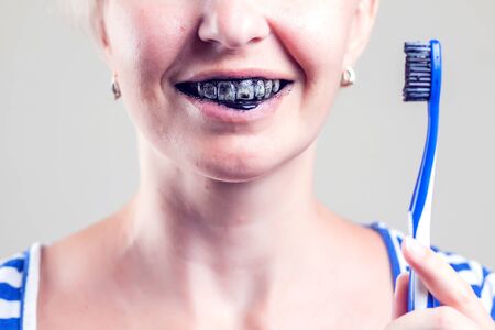 Woman cleans her teeth with charcoal toothpaste. People and healthcare concept.の写真素材