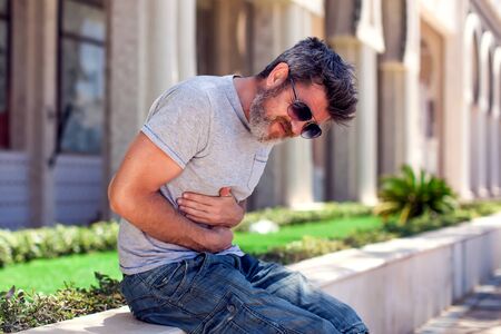 Man having a stomachache while walking on the street. Healthcare, medicine, people conceptの写真素材