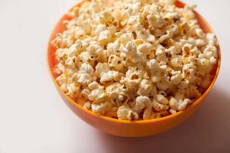 An orange bowl with popcorn isolated on white background. Food conceptの写真素材