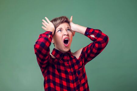 People and emotions - a portrait of young woman with short hair crazy and scared with hands on head,...