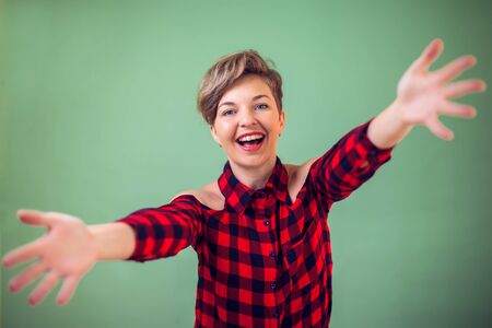People and emotions -a portrait of happy young woman looking at the camera smiling with open arms...