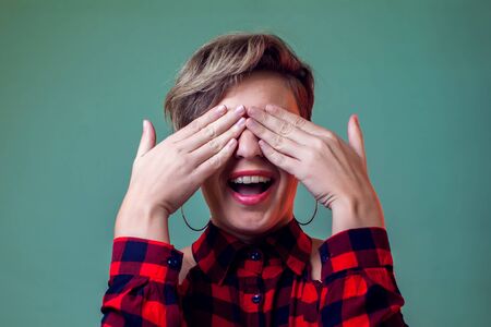 People and emotions - a portrait of smiling young woman with short hair closes her eyes with handsの写真素材