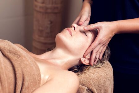 Spa, beauty, people and body care concept - beautiful woman getting face treatment at spa salonの写真素材