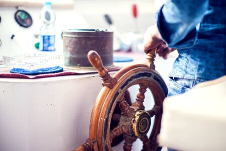 The hands of the captain and a steering wheel boat port services