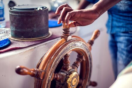 The hands of the captain and a steering wheel boat port services