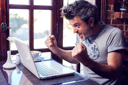 People, technology, communication and leisure concept. Happy man sitting in cafe surfing internet,...