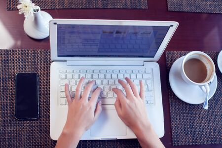 People, technology, communication and leisure concept. Cropped rear view of woman's hands on laptop surfing internet, checking newsfeed via social networks, messaging friends online during lunchの写真素材
