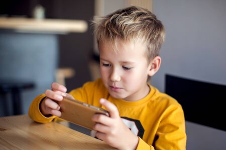 Children, technology and internet concept. Little smiling child boy playing games or surfing internet on digital smartphoneの写真素材