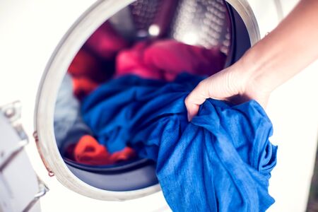 Close-up Of Person Hand Putting Dirty Clothes In Washing Machine For Laundry. Housework and laundry conceptの写真素材