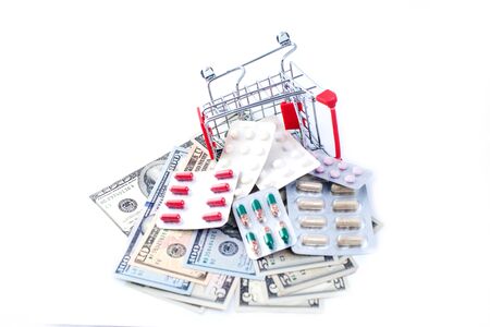 Full small shopping trolley of pills and money on white background. Health and medicine conceptの写真素材