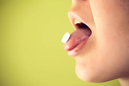 Medicine, health care and people concept - close up of woman taking a pill
