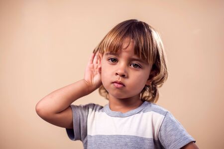 A portrait of  kid boy eavesdropping on a conversation. Children and emotions conceptの写真素材