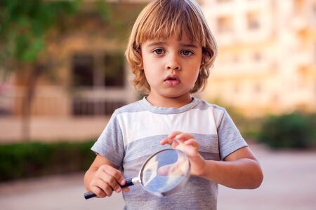A portrait of kid boy holding magnifier. Childhood and discoveries conceptの写真素材
