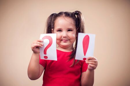 A portrait of kid girl holding cards with exclamation point and question mark. Children and education conceptの写真素材