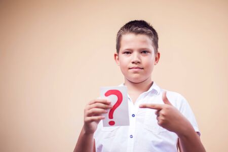 A portrait of kid boy holding cards with question mark. Children and education conceptの写真素材