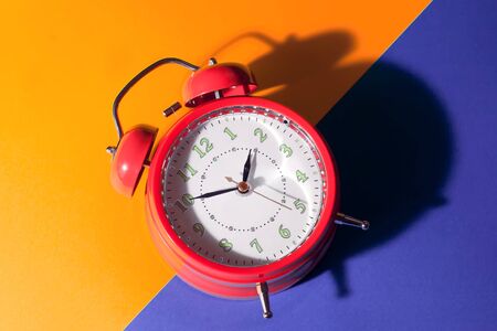 Red alarm clock is on color background. Time concept