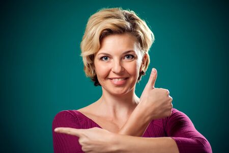 Smiling woman with short blond hair showing thumb up gesture. People, lifestyle and emotions conceptの写真素材