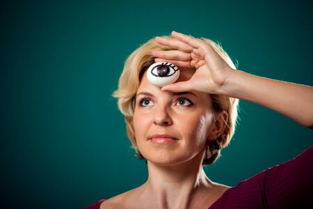 A portrait woman with short blond hairholding egg with drawing eye. Third eye conceptの写真素材