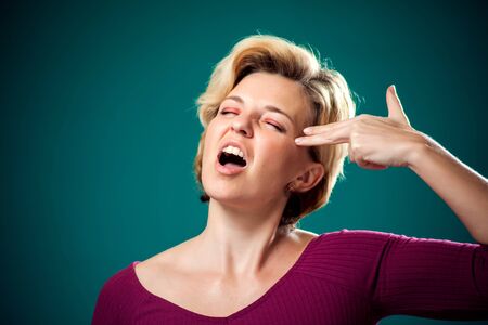 Woman with short blond hair doing gun gesture with fingers. People,lifestyle and emotions conceptの写真素材