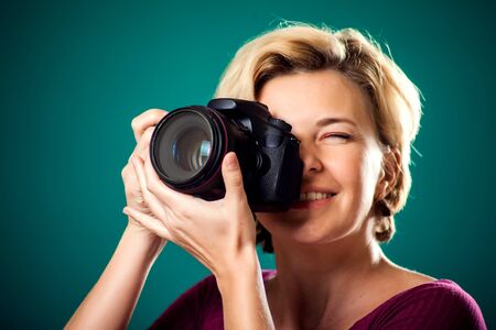 Smiling pretty woman with short blond hair holding photo camera. People, hobby and lifestyle conceptの写真素材