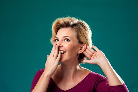 Woman with short blond hair listening and telling gossip. People, lifestyle and emotions concept