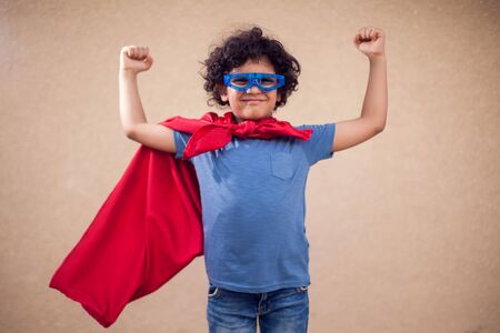 A portrait of kid boy with curly hair in costume of superhero. Childhood and success conceptの写真素材