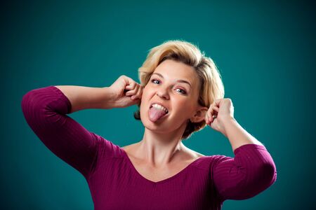 Funny-looking woman with short blond hair making funny face showing tongue and ears. People, lifestyle and emotions conceptの写真素材