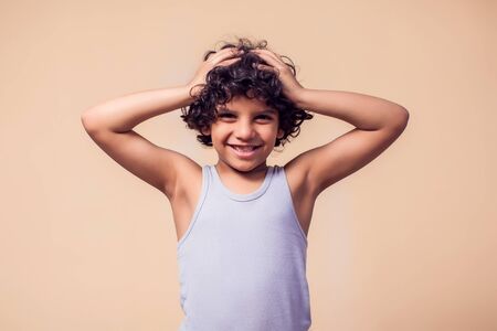 A portrait of smiling kid boy with curly hair. Children and emotions conceptの写真素材