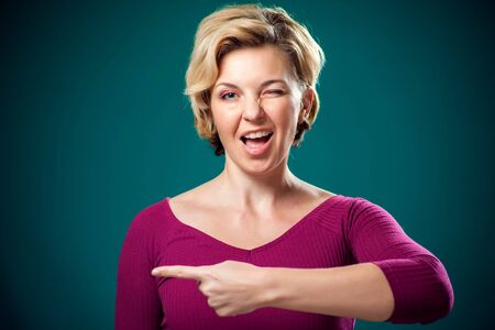 Smiling woman with short blond hair point finger to the side. People, lifestyle and emotions conceptの写真素材