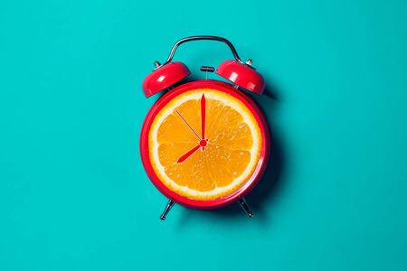 Red alarm clock with orange fruit on the place of watch dial. の写真素材