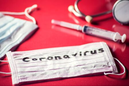 Mask with word-coronavirus, medicine items on red background. Medine and healthcare conceptの写真素材