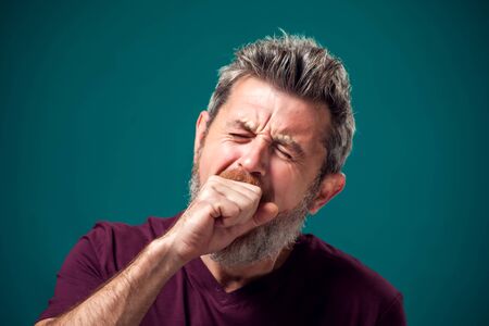 A portrait of bearded yawning bored man in red t-shirt. People and emotions conceptの写真素材