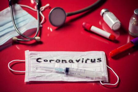 Mask with word-coronavirus, medicine items on red background. Medine and healthcare conceptの写真素材