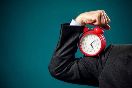 Bearded businessman in suit holding red alarm clock. Time management conceptの写真素材