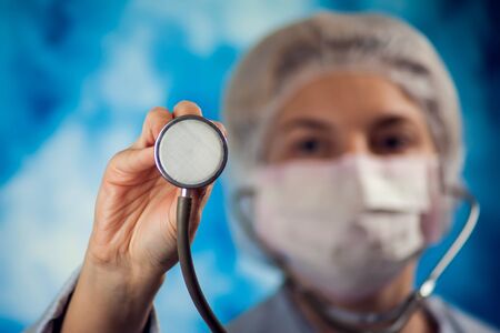 female doctor in blue medical gloves holding phonendoscope. People, medicine and healthcare conceptの写真素材