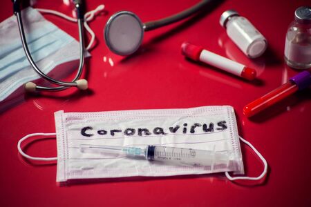 Mask with word-coronavirus, medicine items on red background. Medine and healthcare conceptの写真素材