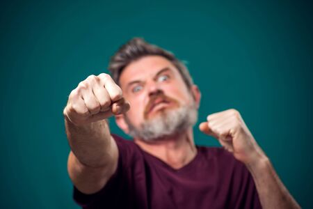 A portrait of bearded angry man in red t-shirt showing fist at camera. People and emotions conceptの写真素材