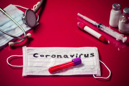 Mask with word-coronavirus, medicine items on red background. Medine and healthcare conceptの写真素材
