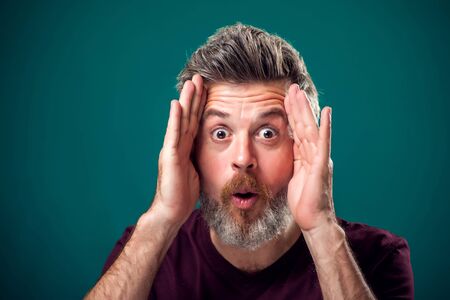 A portrait of bearded surprised man in red t-shirt. People and emotions concept